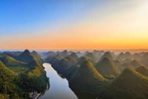 Aerial view of karst peaks and a winding river at sunset in Anshun, Guizhou, China.