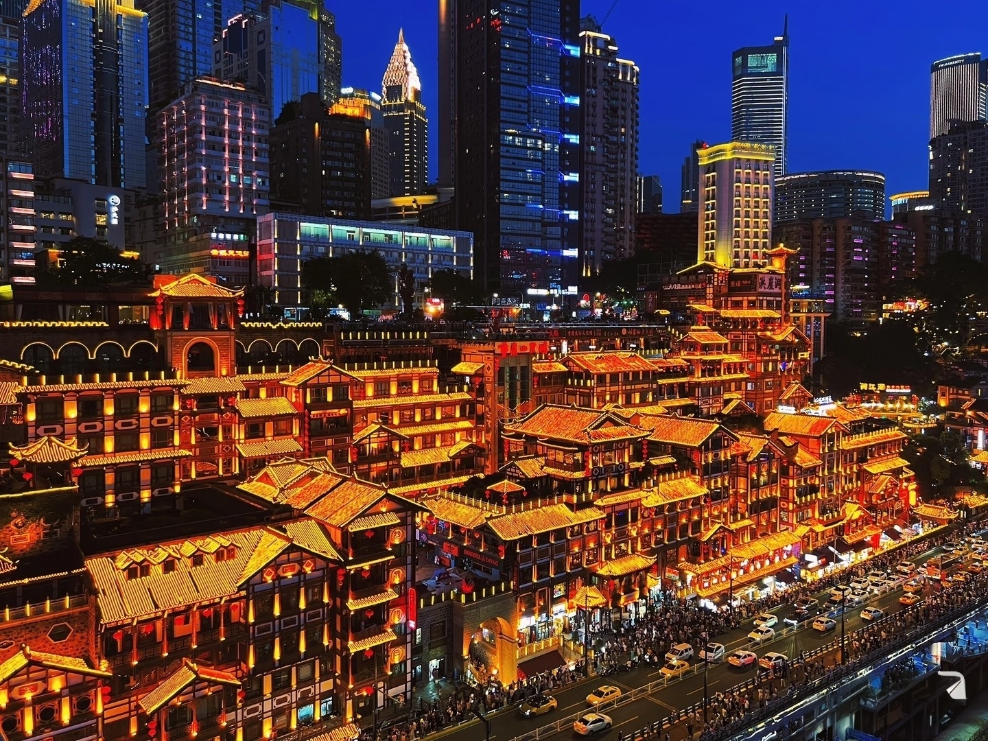 Illuminated traditional Chinese architecture of Hongyadong contrasts with modern skyscrapers in a vibrant night view of Chongqing, China.