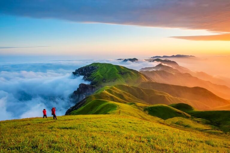 Two photographers capture the stunning sea of clouds and rolling green alpine meadows at sunrise on Wugong Mountain, Pingxiang, Jiangxi, China.